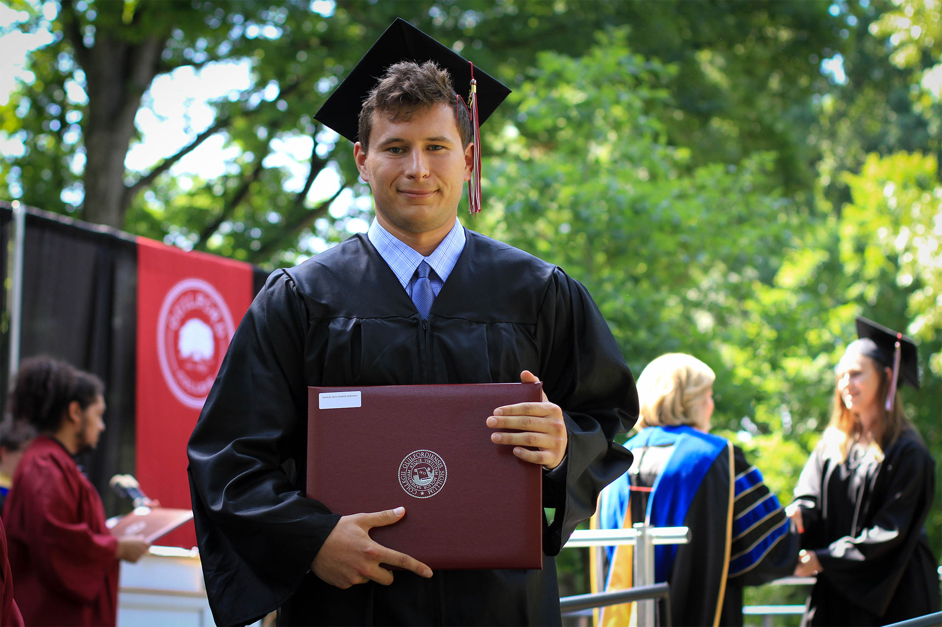 A graduate poses for the camera after receiving his diploma.