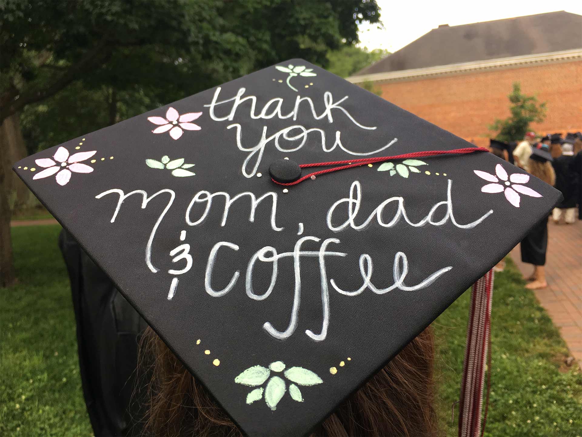 A student's mortarboard reads, "Thank you, Mom and Dad and Coffee."