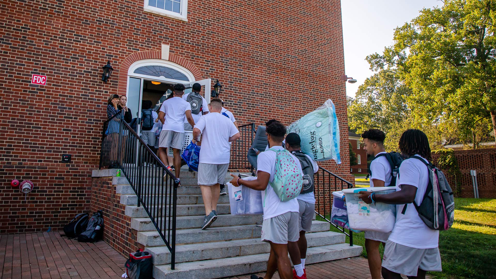 Members of the College football team help students move in to Binford Hall.