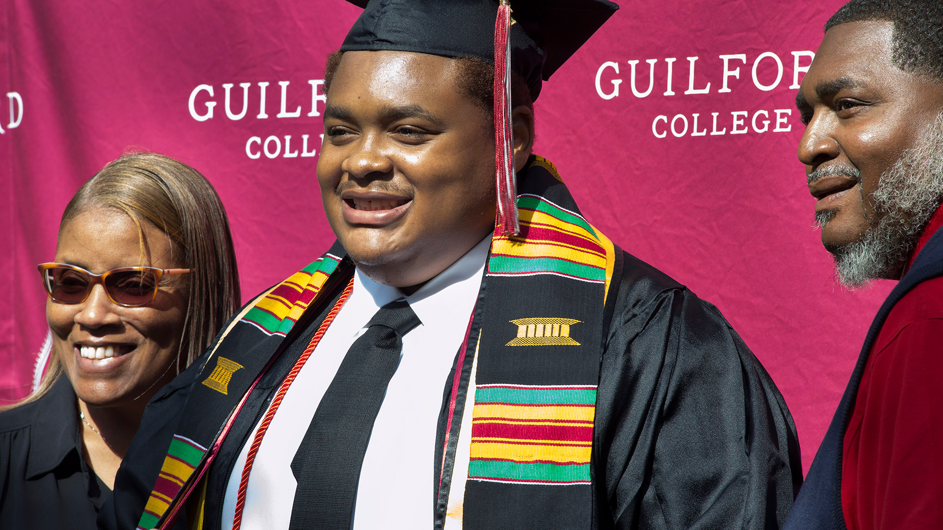 A member of the graduating class is all smiles in this photo with parents.