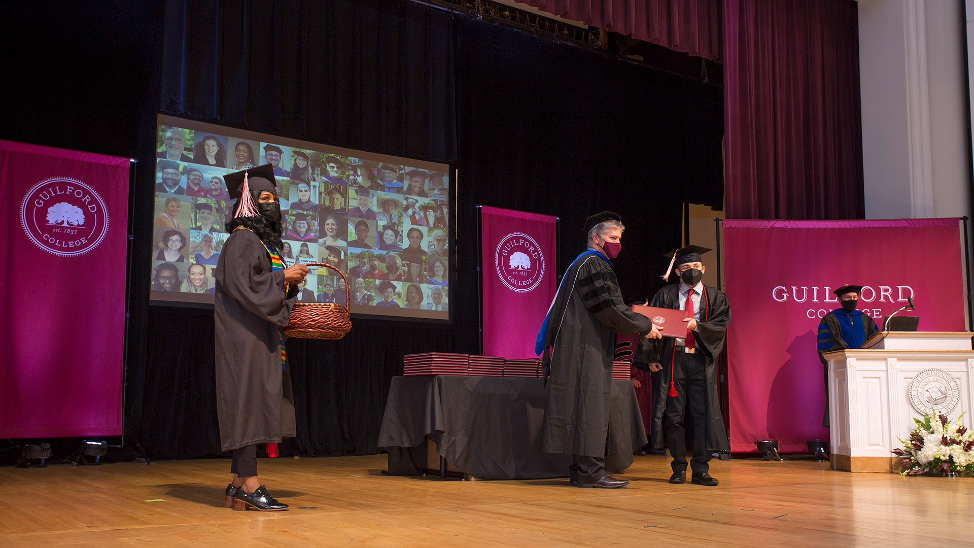 A graduate stands on stage in Dana Auditorium.