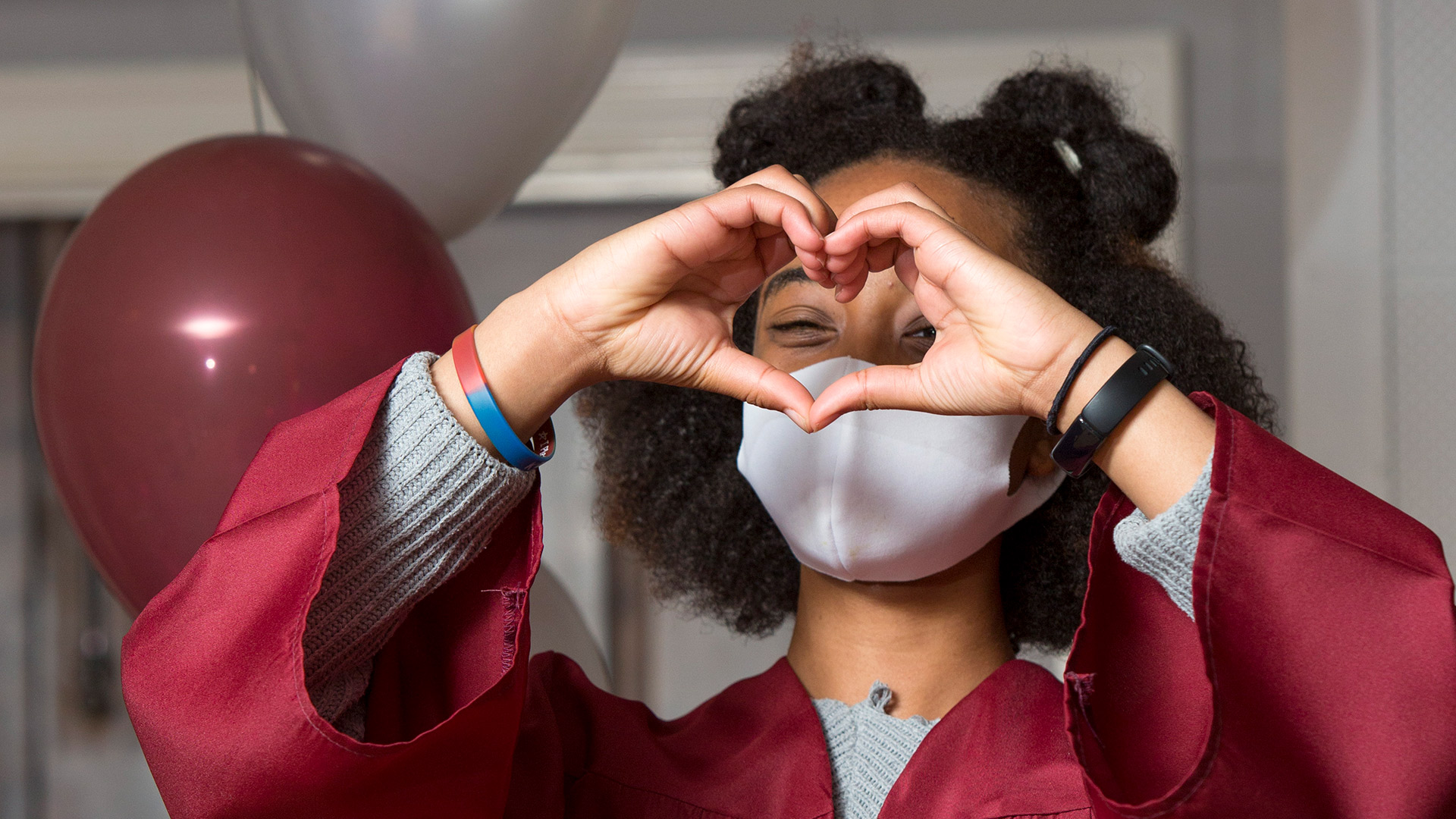 A junior makes a heart sign with their hands at Commencement.