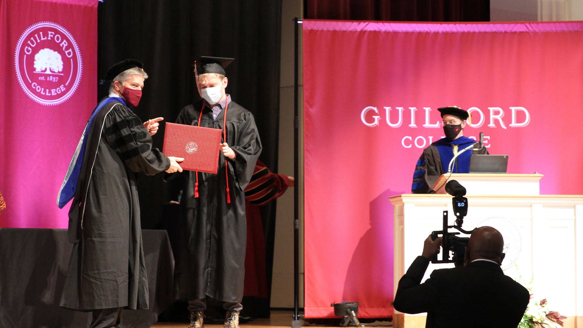 A student receives their diplomas on stage in Dana Auditorium.