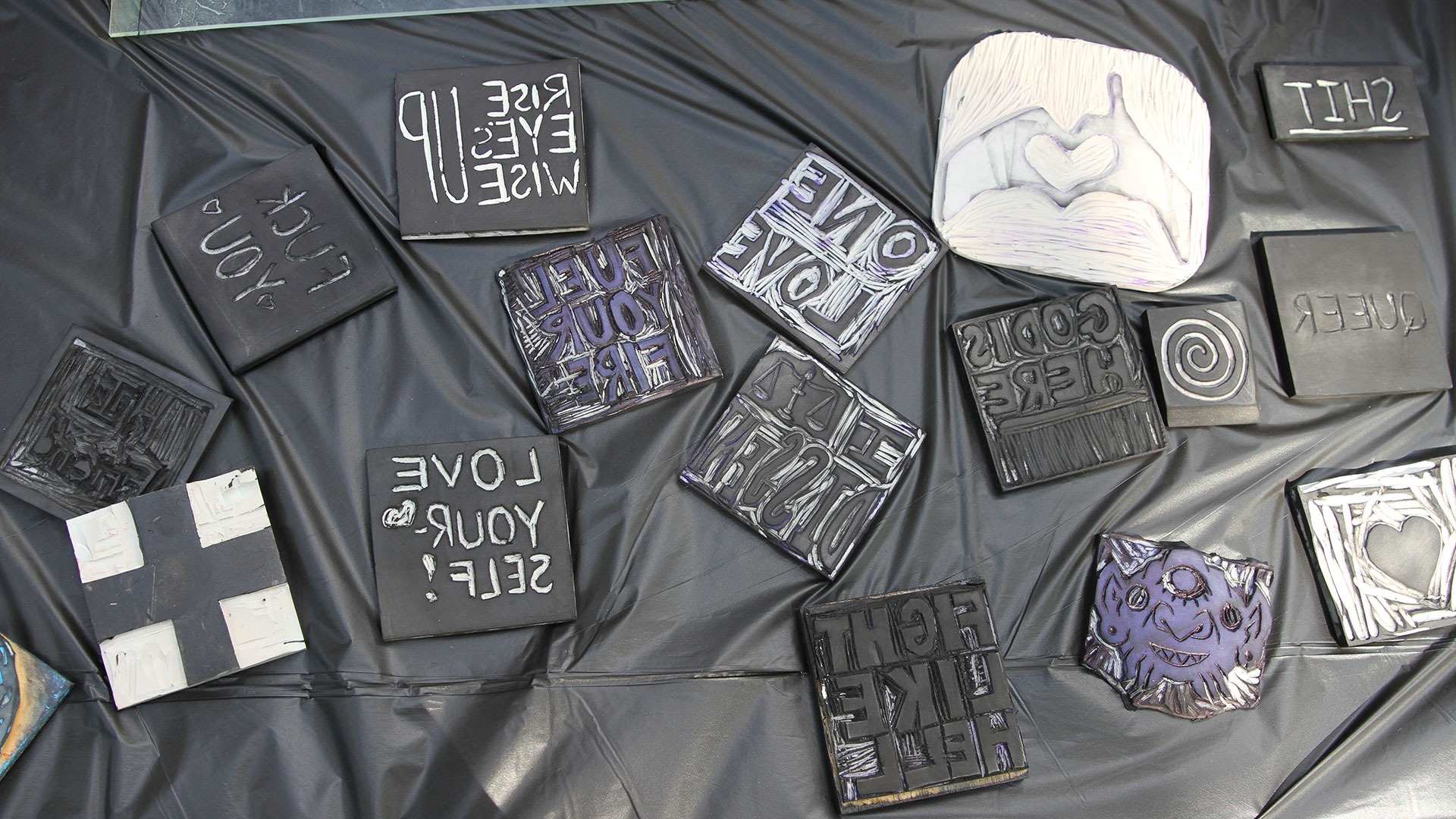 A pile of sticker templates sit on a table covered in a black plastic cloth.