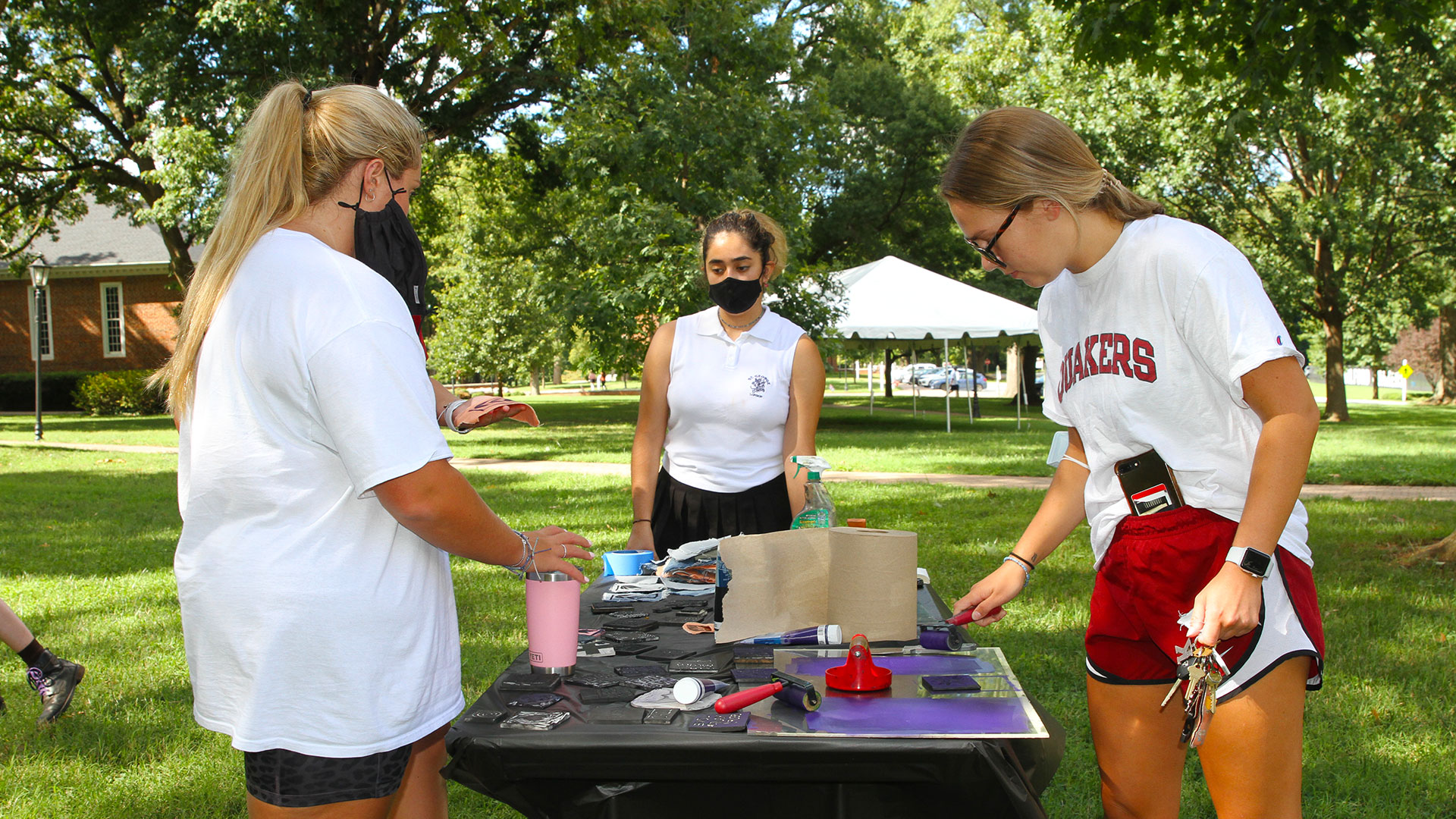 Three students make decals at Free Press on the Quad.