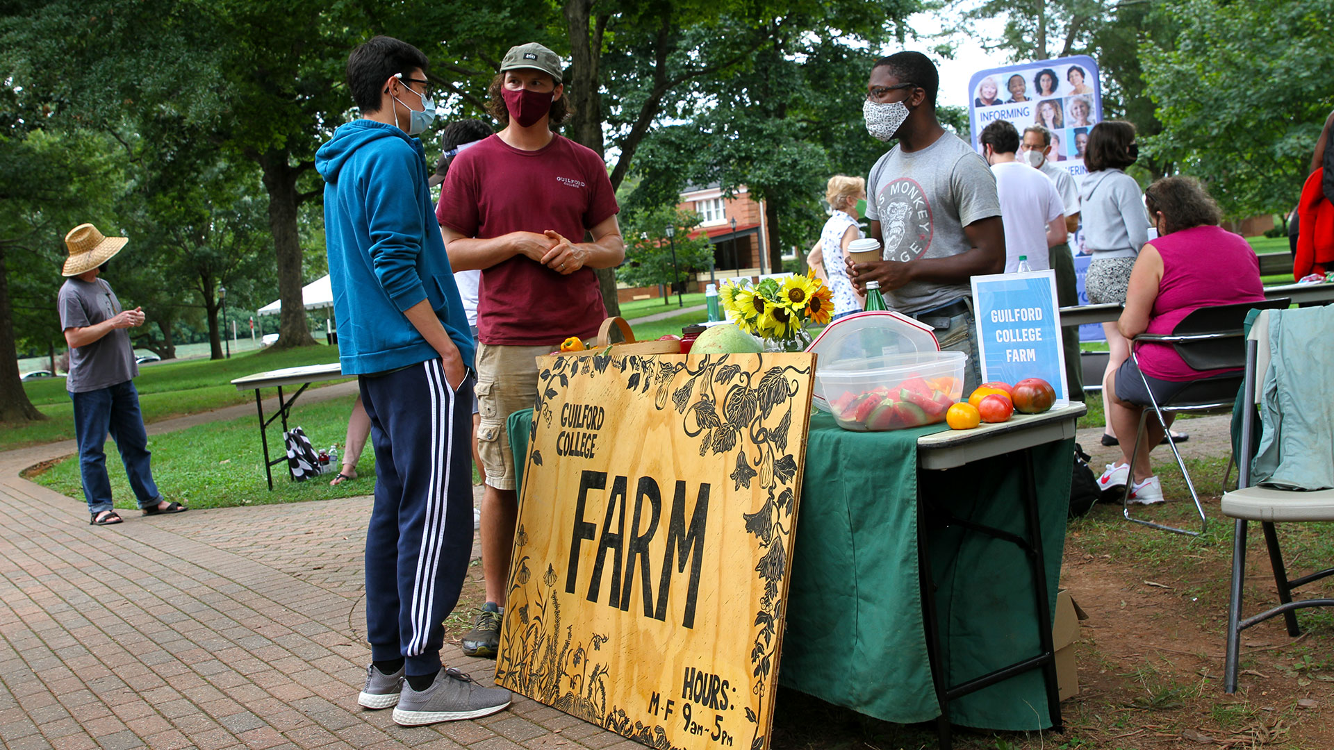Students stop by the College Farm table to talk with the campus farmer.