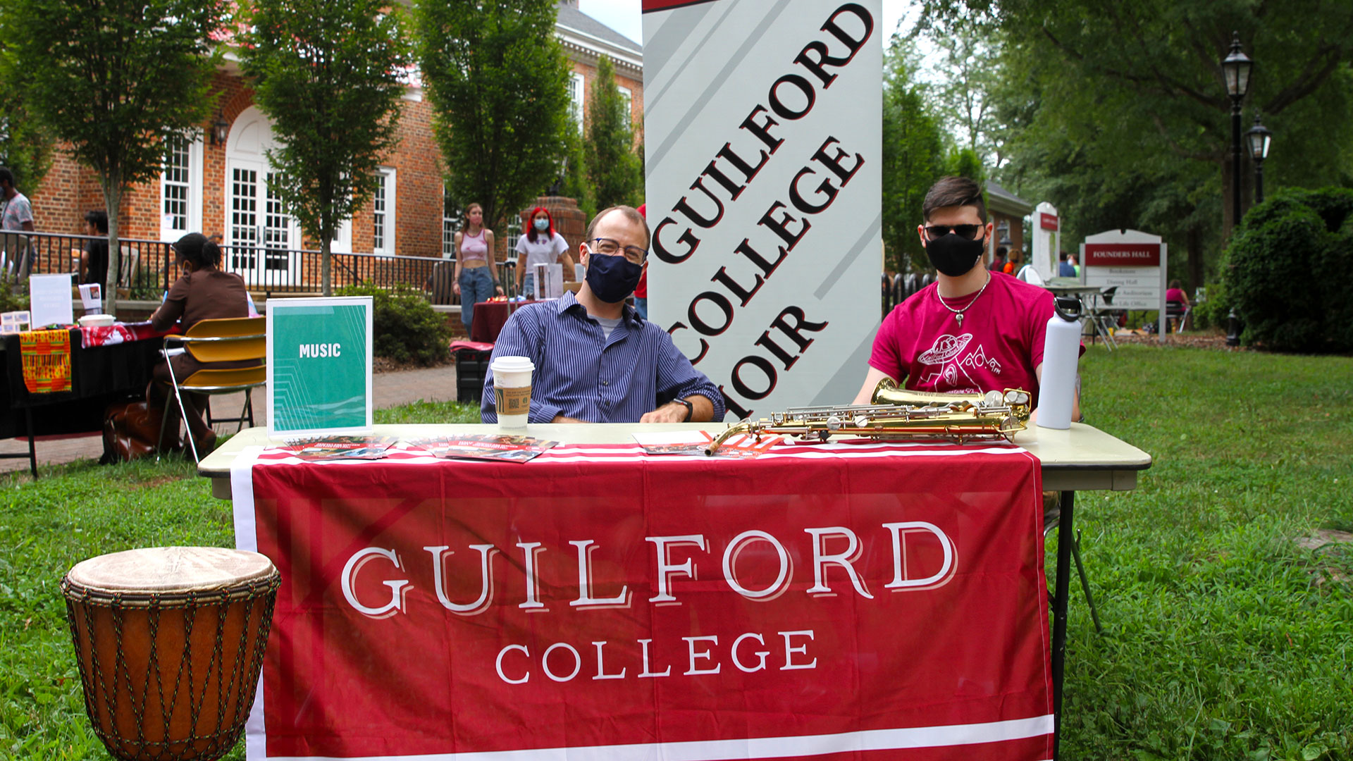 Music Professor Drew Hays and a student sit at the Guilford College Music and choir table.
