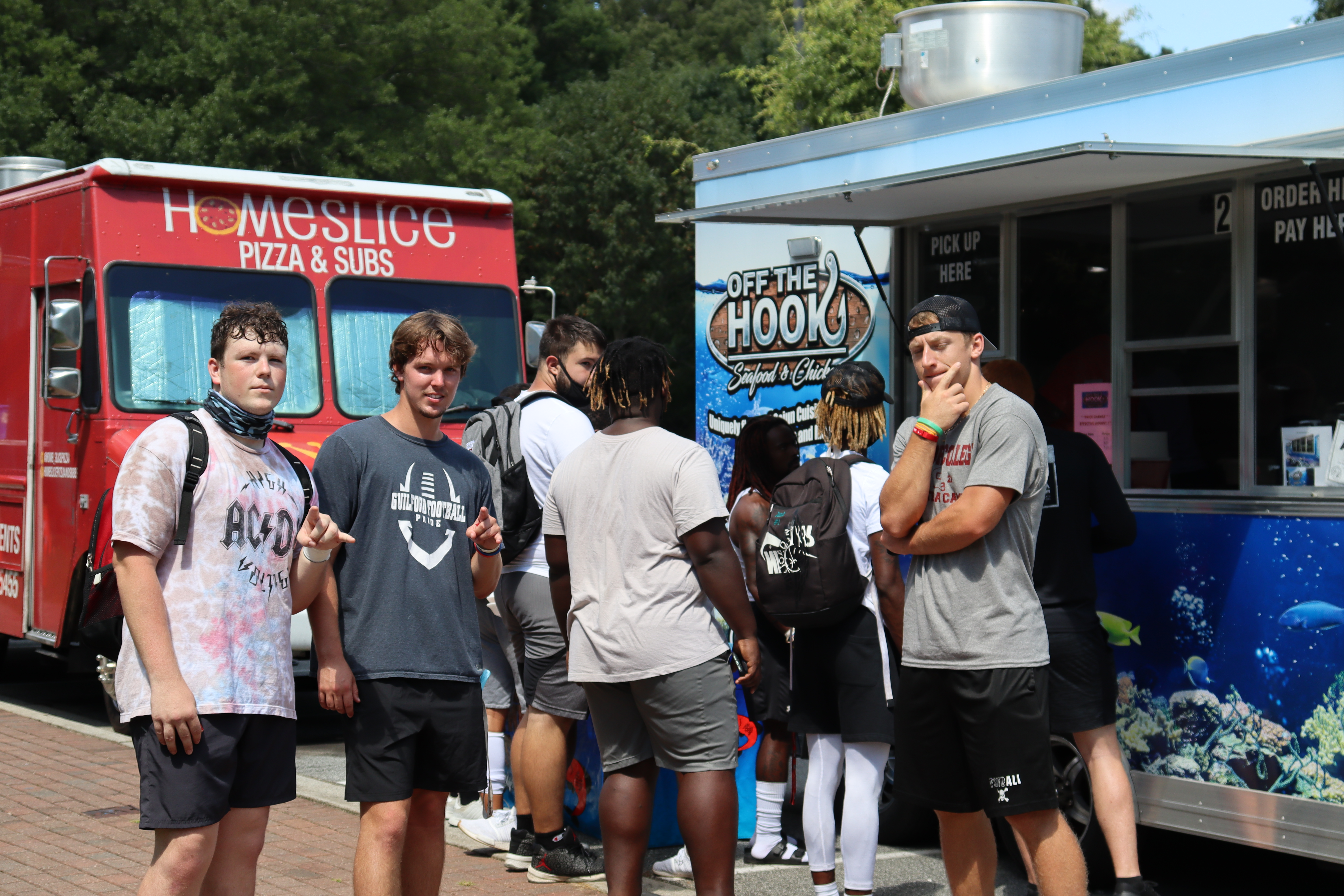Students take a group photo in front of the food trucks at the WOW kickball and food truck event.