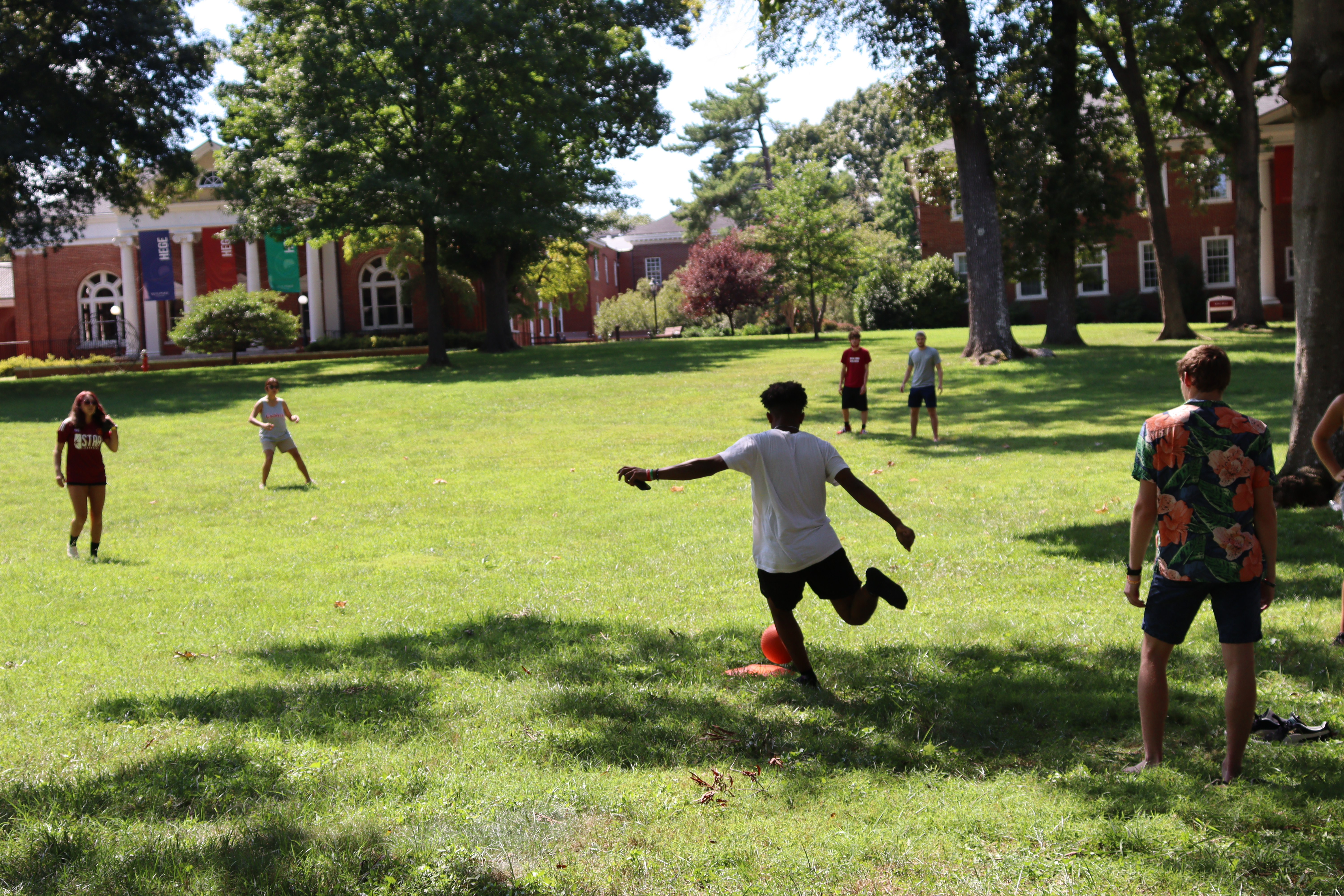 A student kicks the ball during a kick ball game on the Quad.