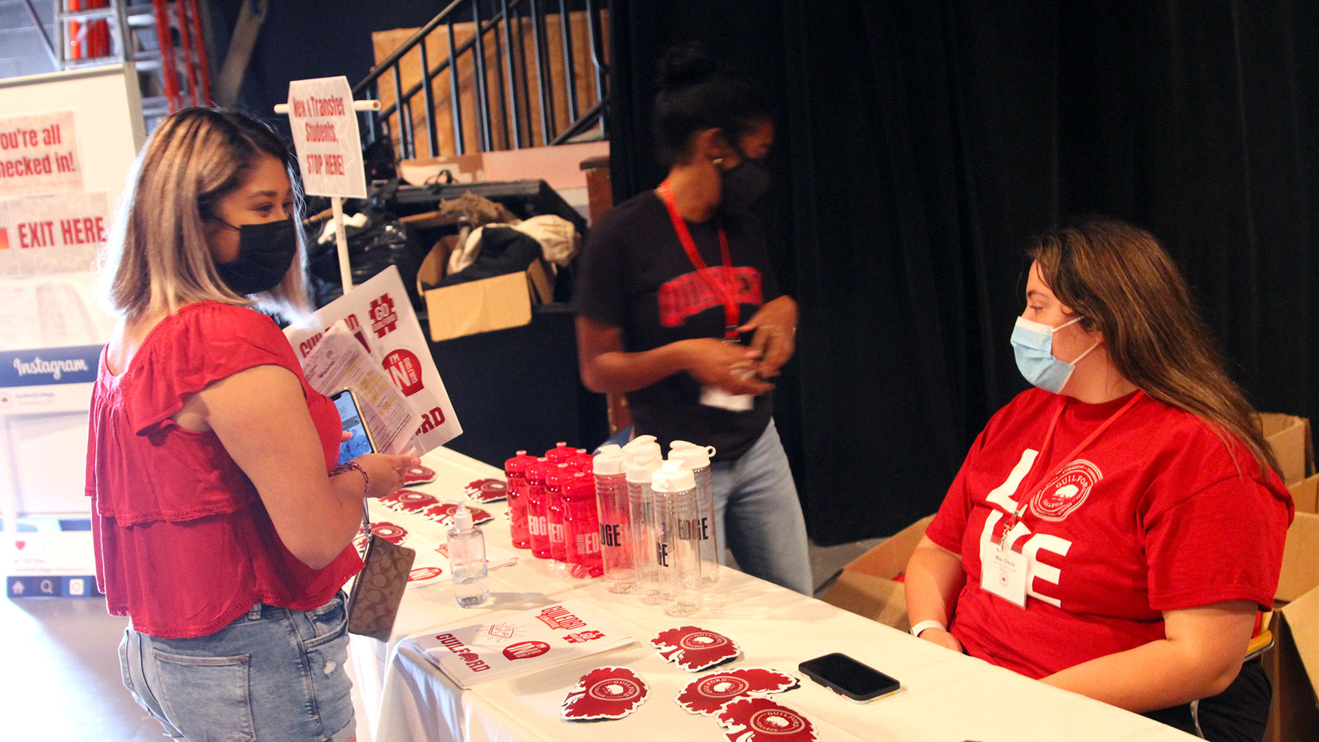 A student stops by the free Guilford swag table to pick up decals and a water bottle.