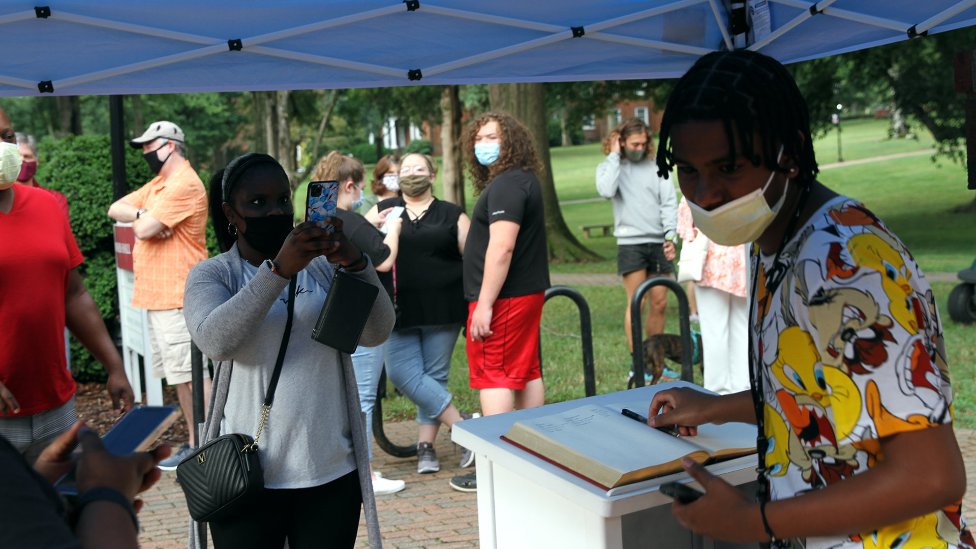 A mother takes a photo of her son at the registration table outside of Founders Hall.