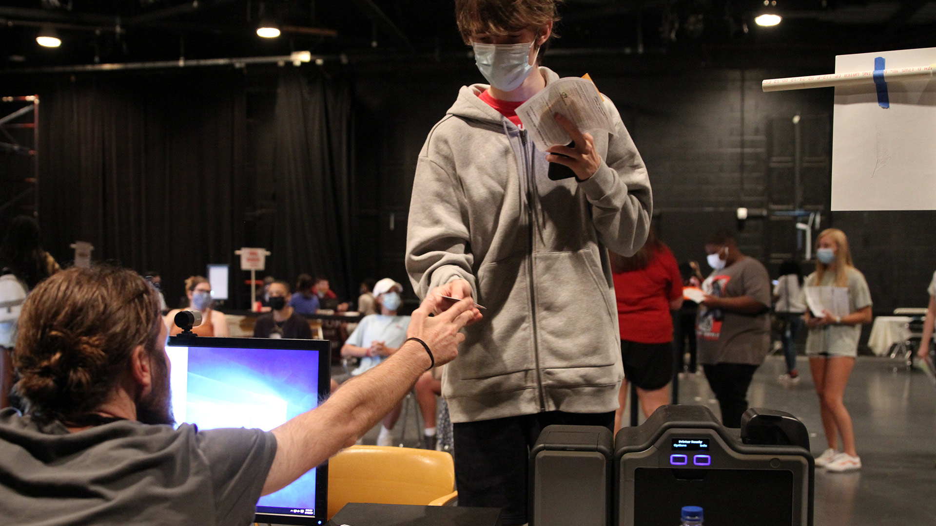 A staff member hands a student their new Quaker Card ID.