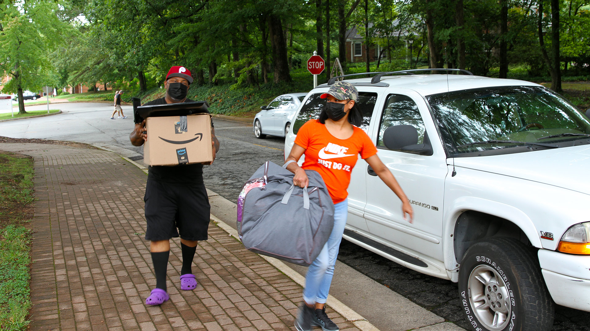 A parent helps their student carry in boxes of belongings.