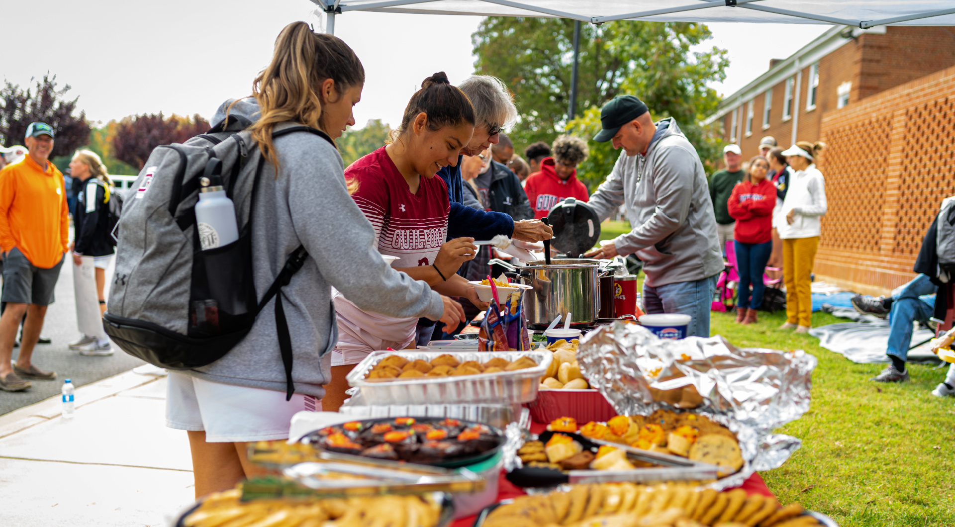 Members of the women's soccer team go through a line at tailgaiting.