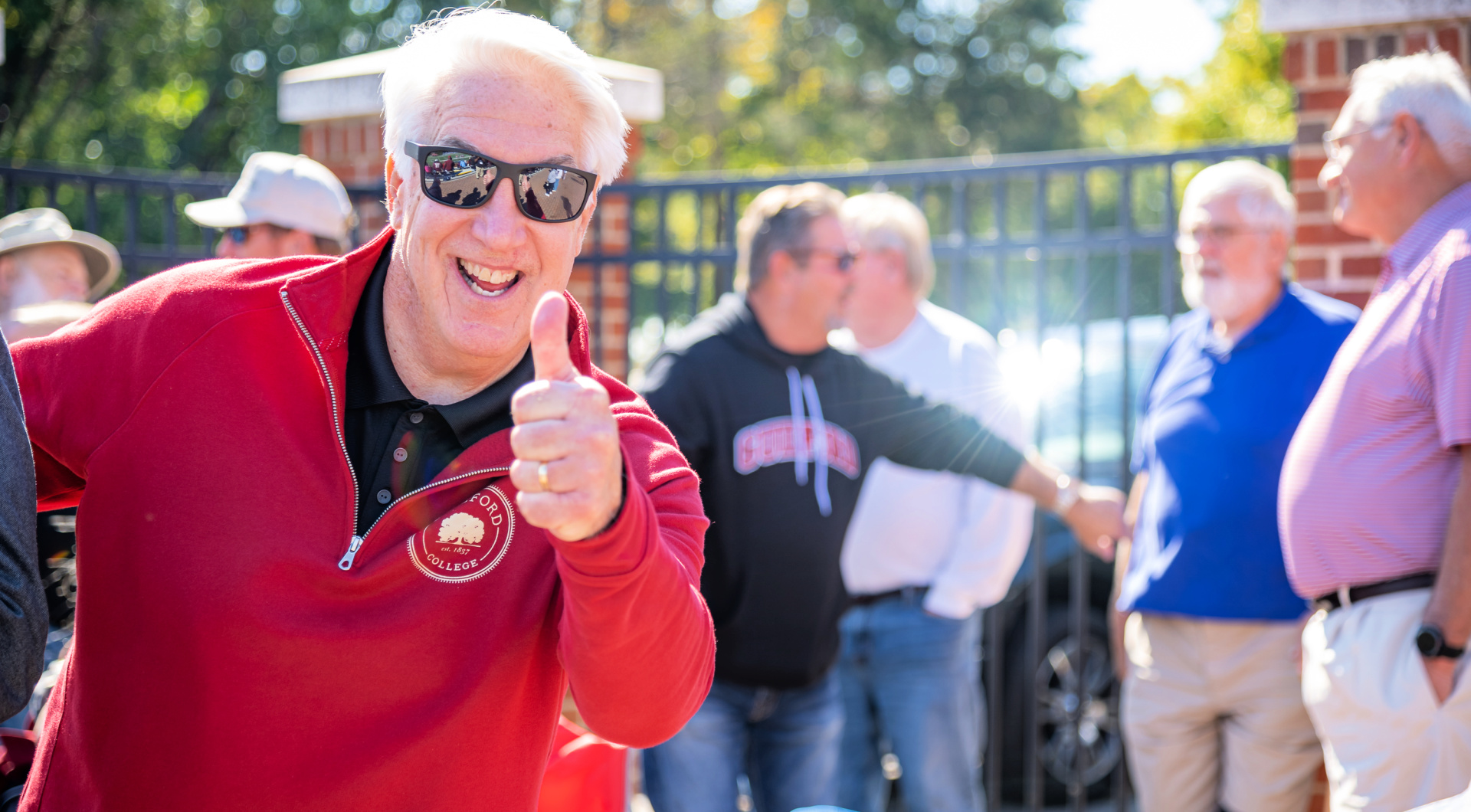 A Guilfordian gives a big smile and a thumbs up to the photographer.