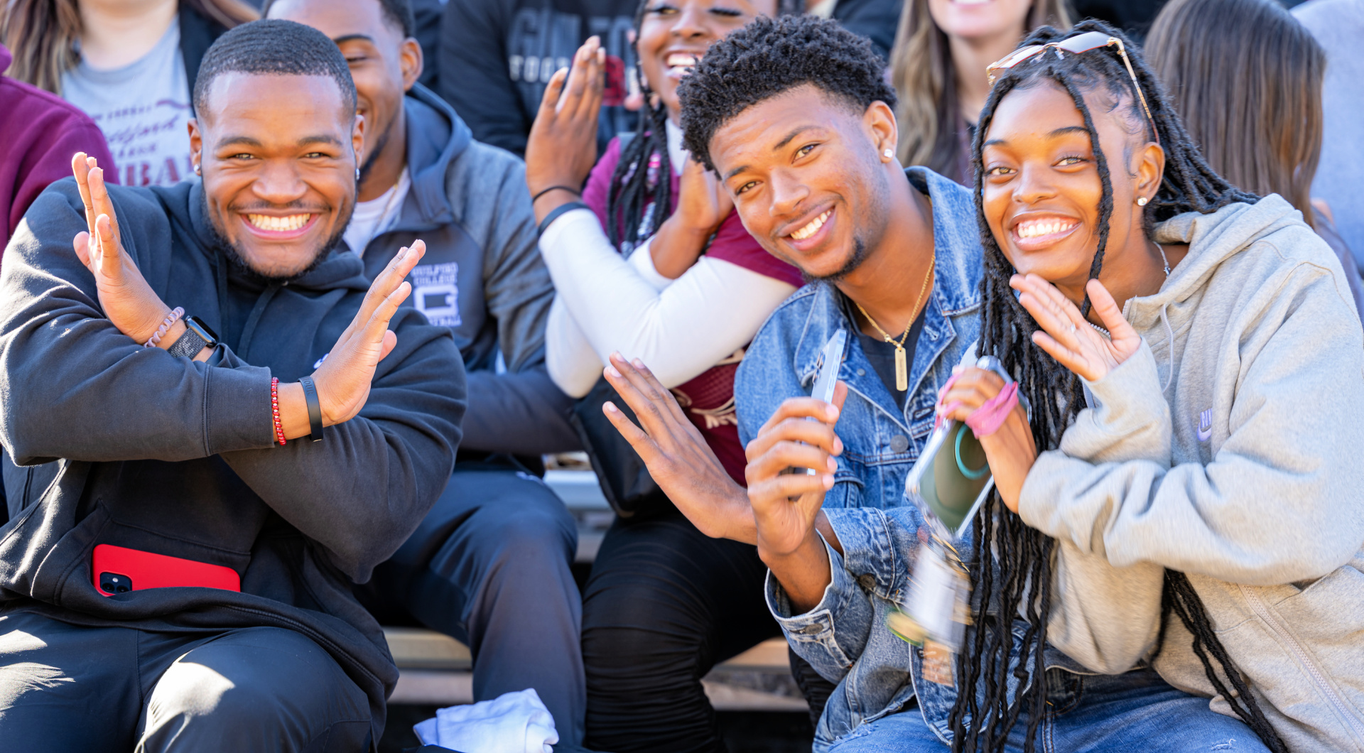 Three students smile from the stands.