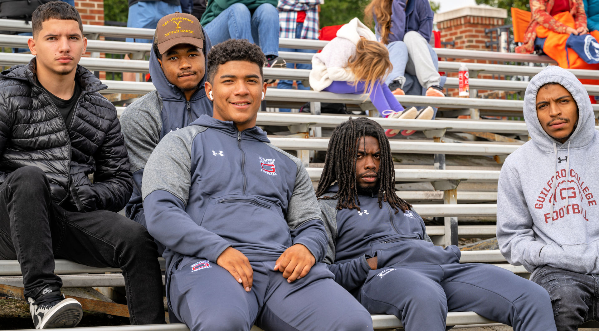 Five Guilfordians sit in the stands during the homecoming soccer match.