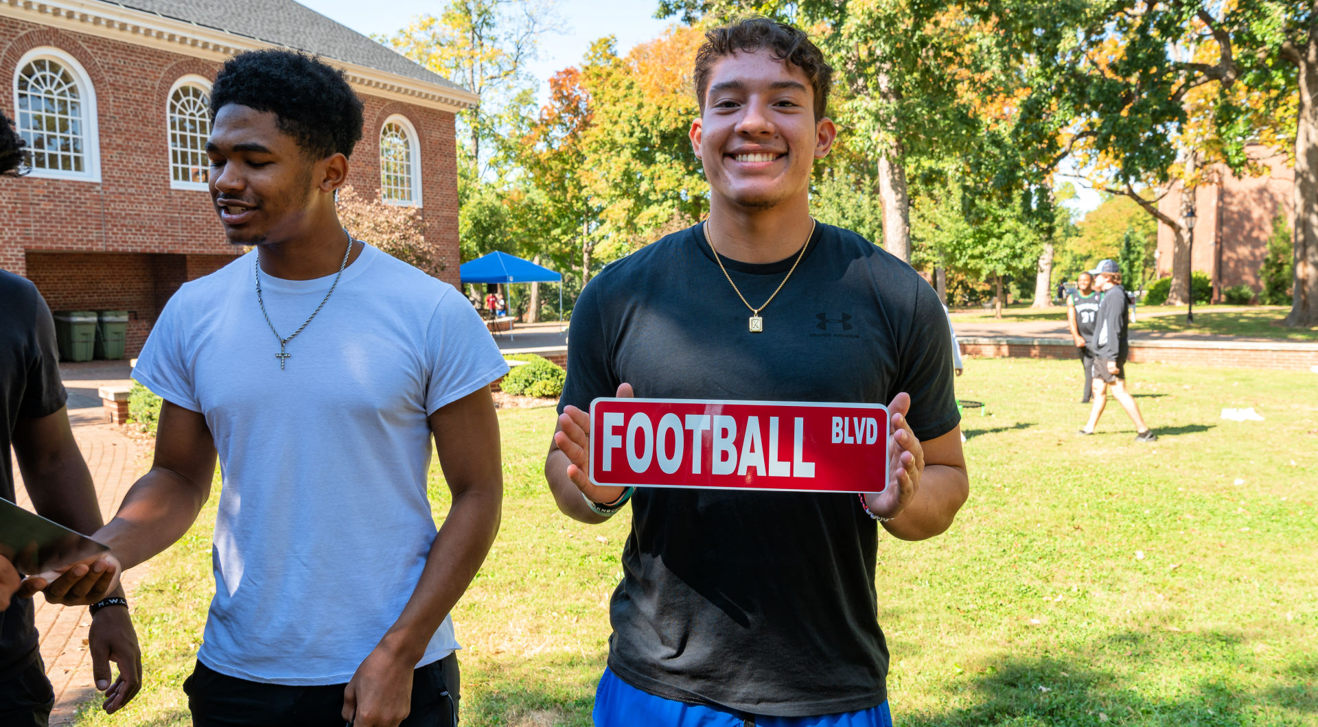 A Guilford student holds a road sign they made that says Football Boulevard.