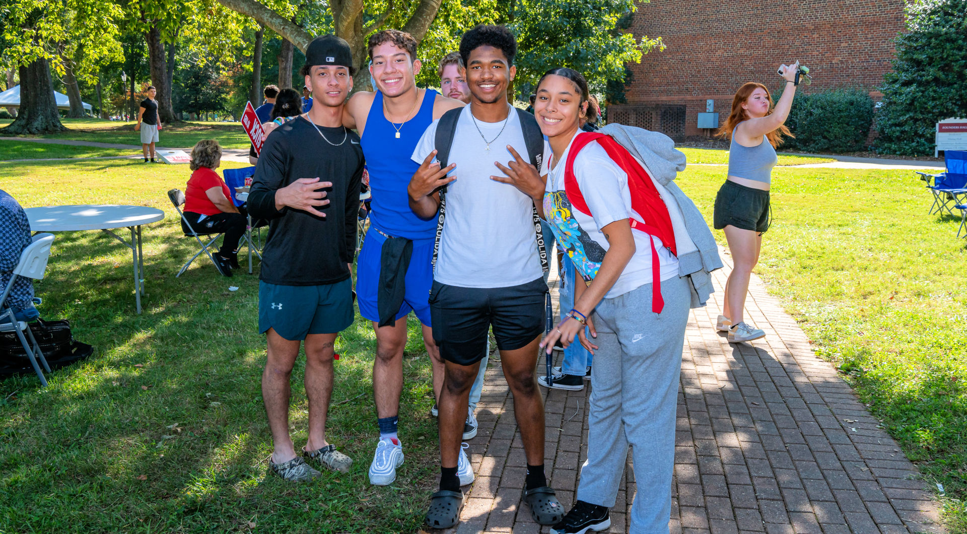 A group of four students takes a photo outside of Founders Hall during Homecoming events.