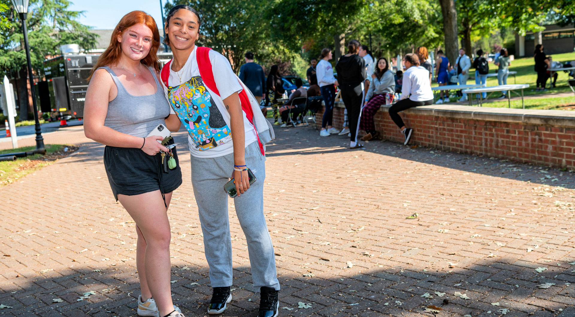 Two students take a photo outside of Founders Hall.