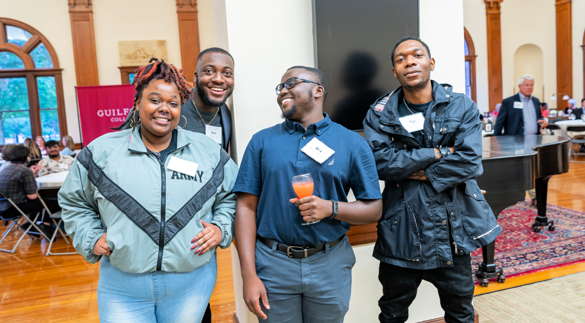 Four students take a group photo outside of the Carnegie Room.