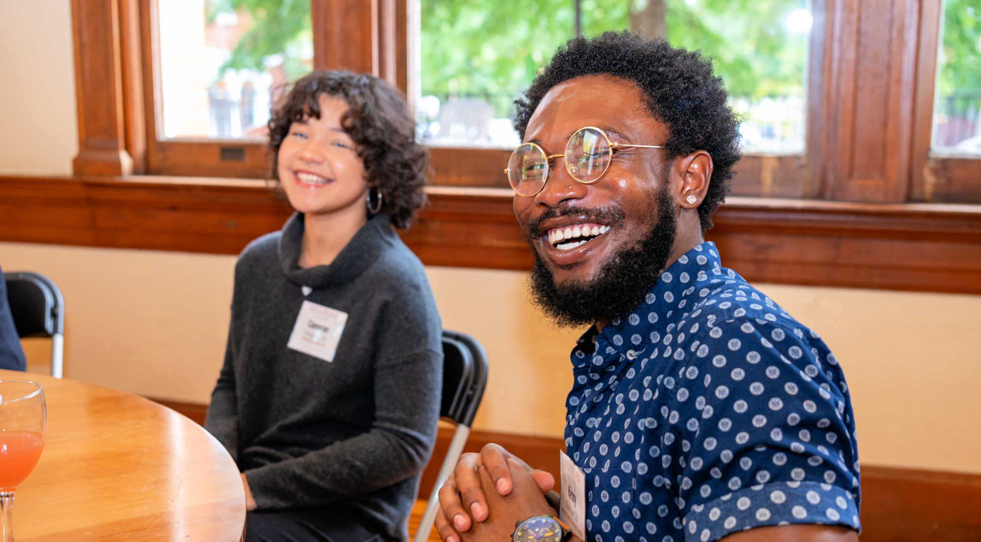 Two students sitting at a table in the Carnegie Room smile at the camera.