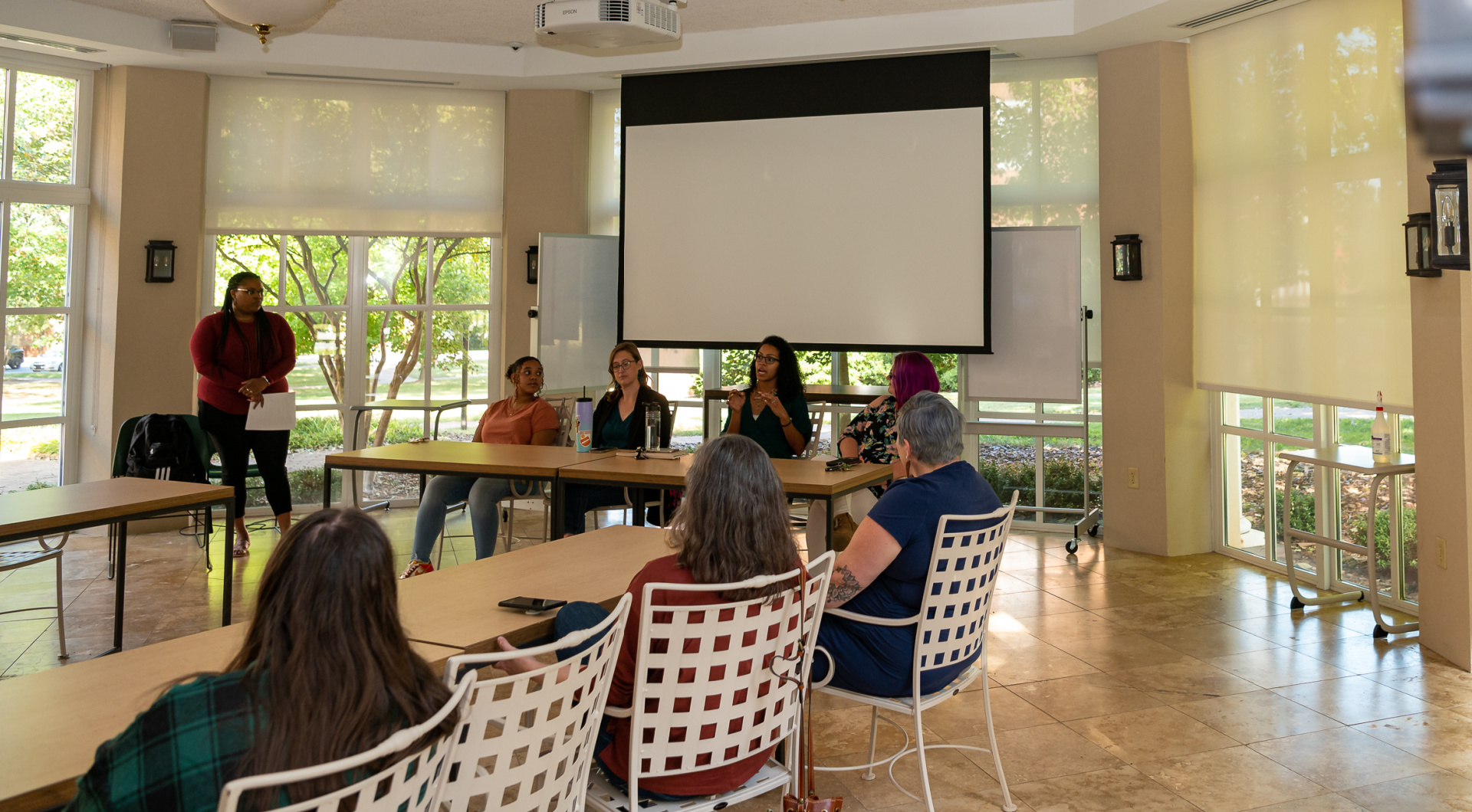 Four alumni sit at a table in the front of the Binford Orangerie during a panel presentation.