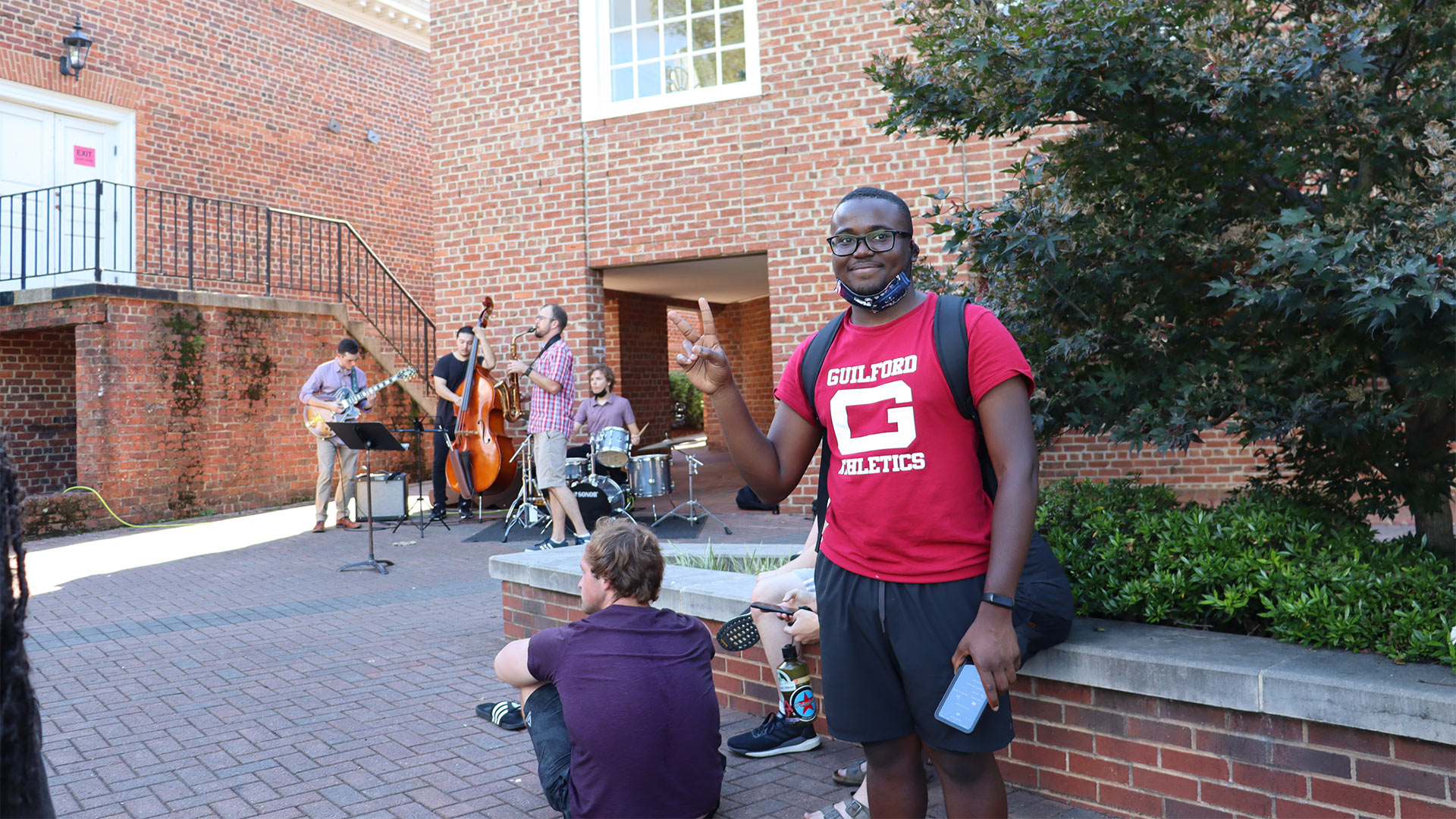 Deon McFarland '24, wearing a red Guilford t-shirt gives the peace sign to the photographer.