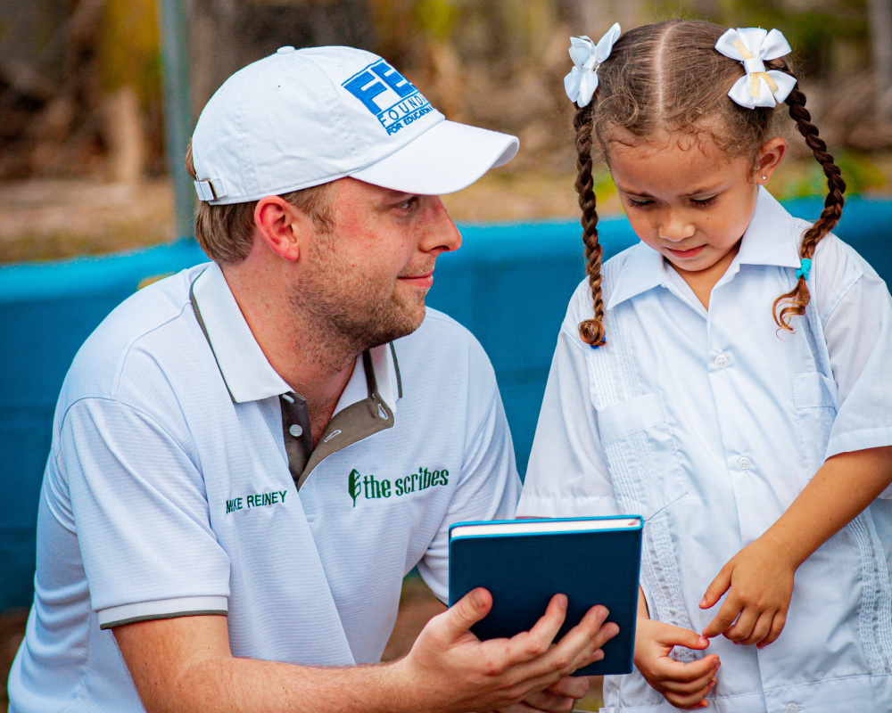 Mike Reiney showing a Scribes notebook to a young girl.