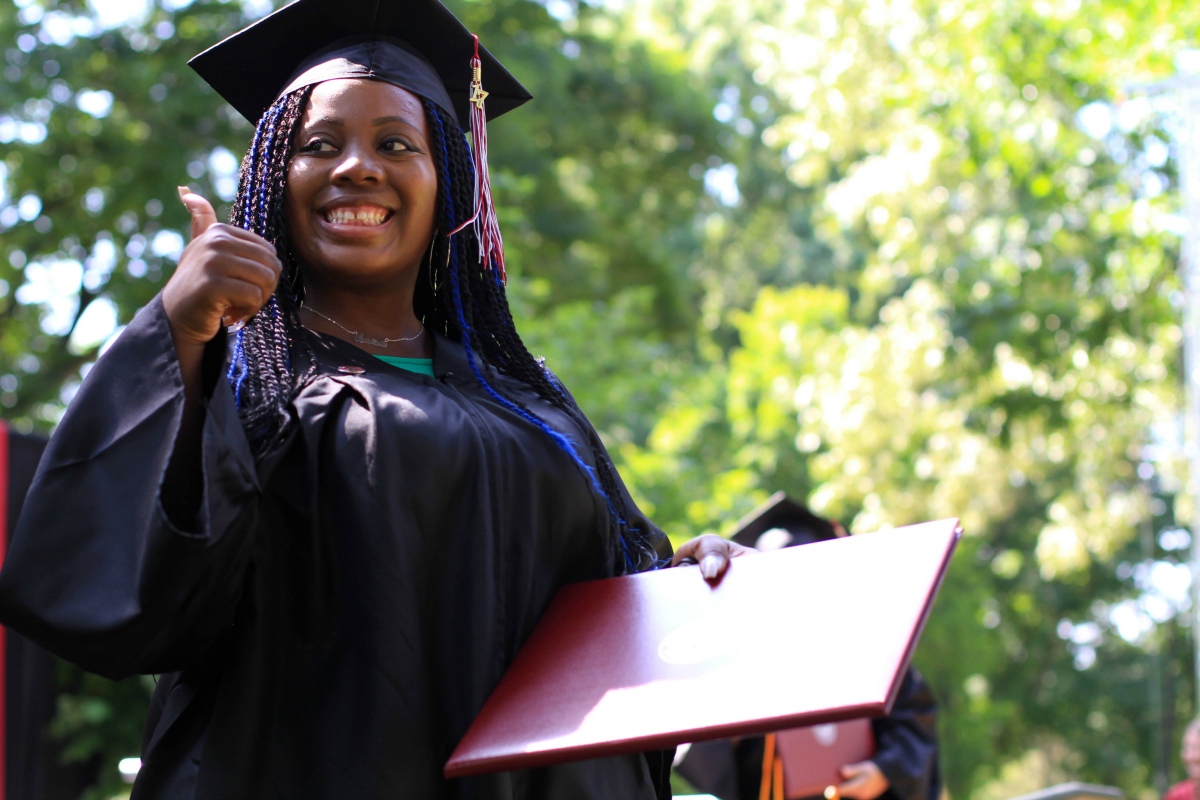 A student flashes a thumbs-up sign after accepting her diploma..