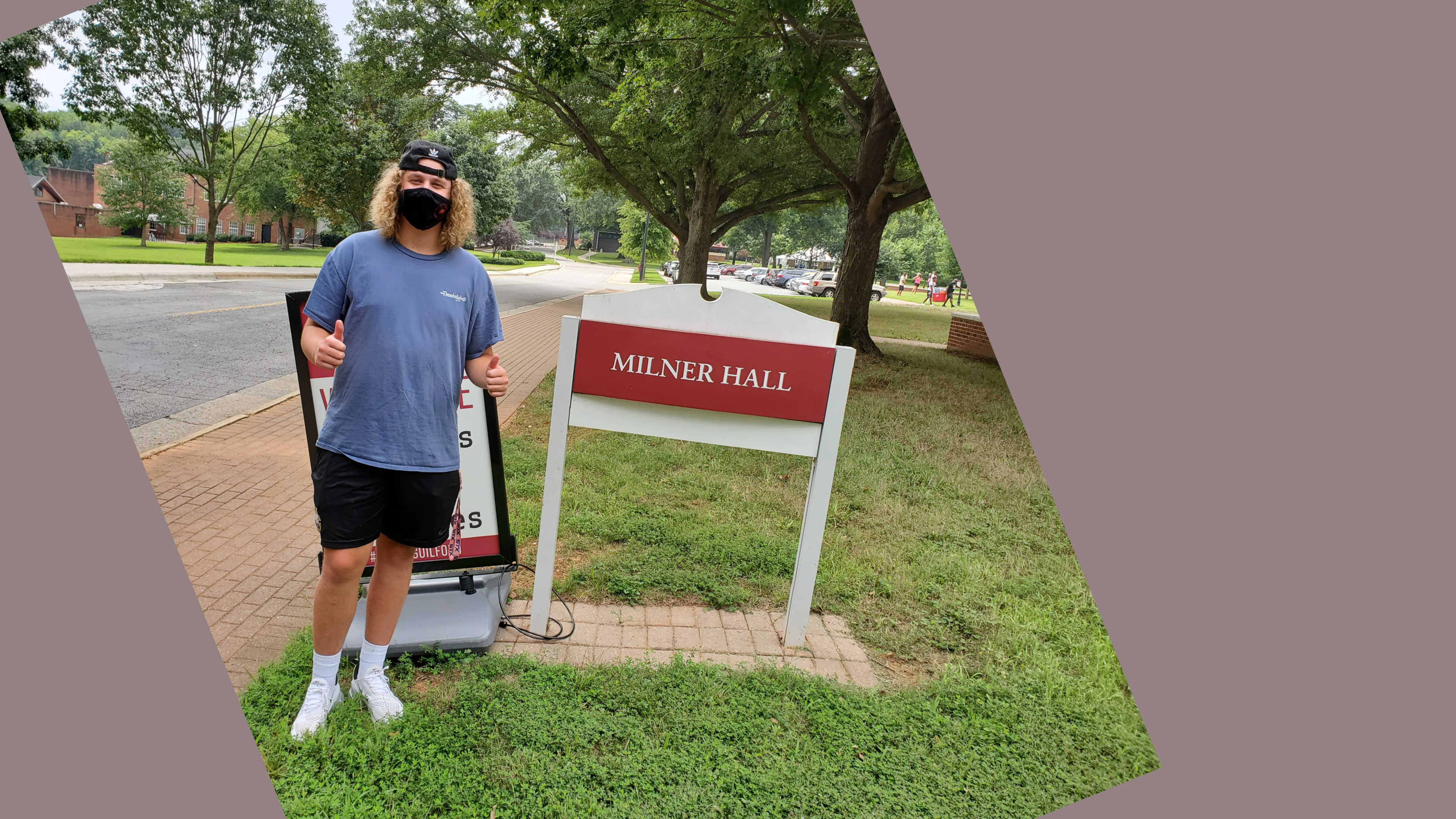An excited student poses for a photo outside of Milner Hall.