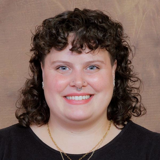 Shyla Butler in black in front of a mottled brown background