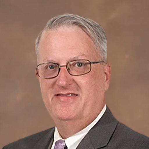 William Hatchett in a dark brown suit and lilac tie