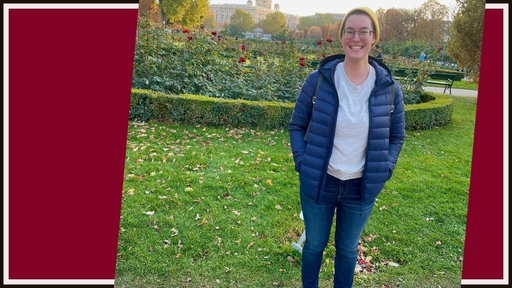 Nita Tyndall '20 stands outdoors on a green lawn wearing glasses, a hat, jeans, a gray tee, and a puffy blue jacket.